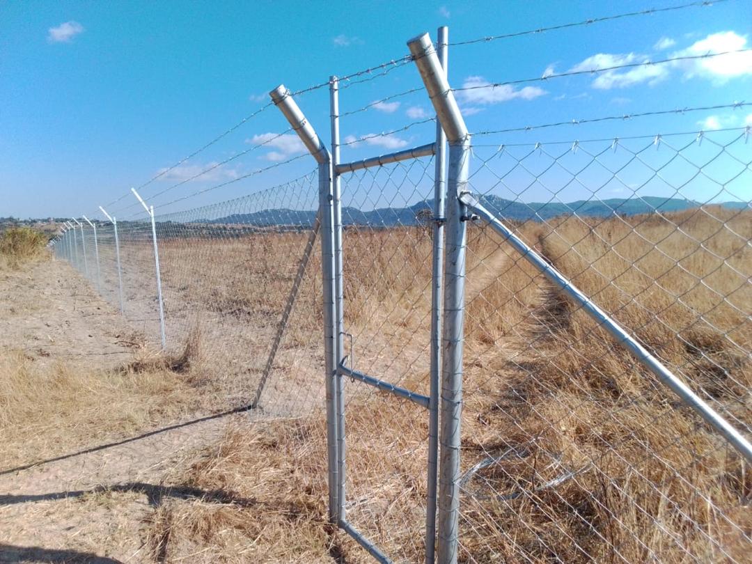Azzar diamond mesh boundary topped with barbed wire